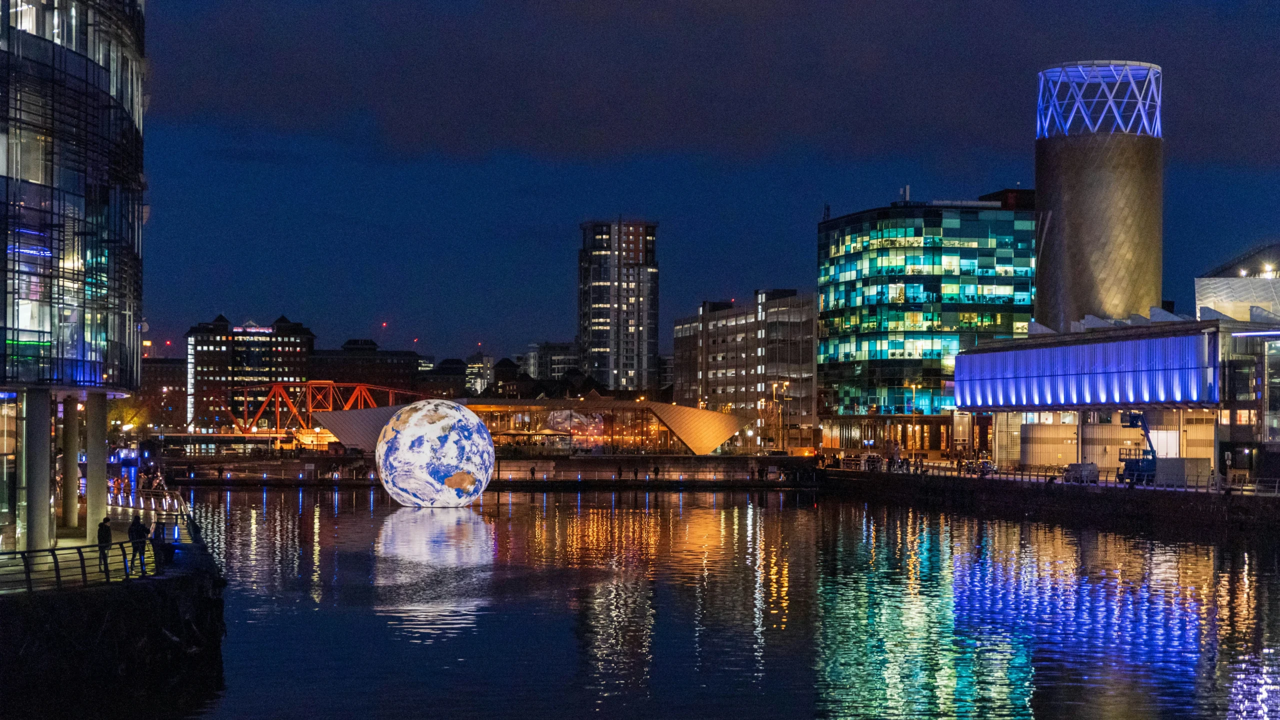 media city home of IT service provider, at night, with a large light up globe in the water