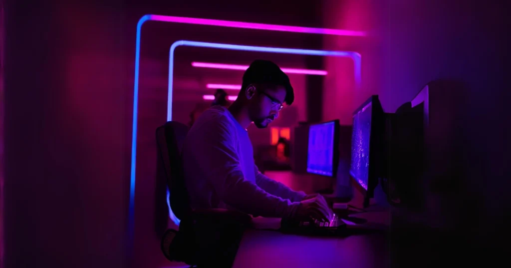 man using computer in a low lit internet cafe office.